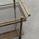 Mid Century Modern bar cart with 2 levels in brass and tinted glass.
