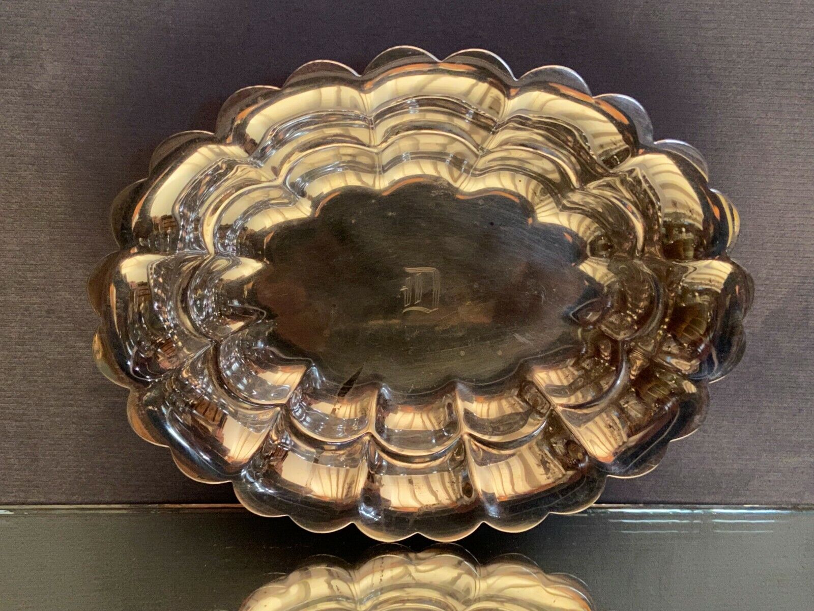 Oval-shaped polylobed metal cup with silver patina engraved with the letter D