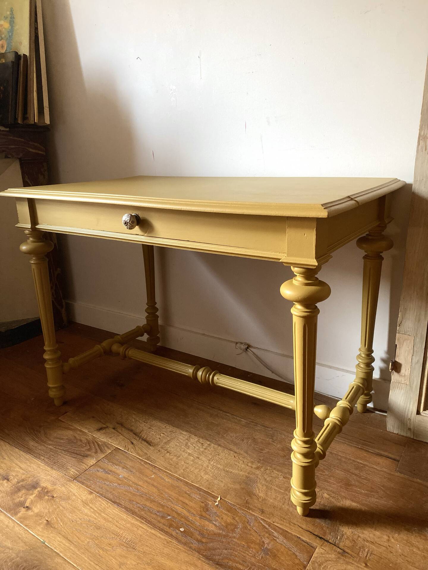 Desk table from the late 19th century, painted mustard, with turned stretcher.