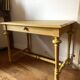 Desk table from the late 19th century, painted mustard, with turned stretcher.