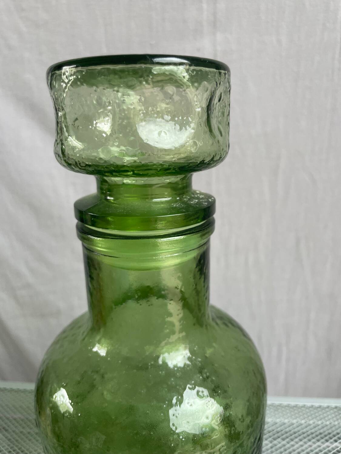 Green glass bottle with craters