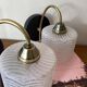 Pair of wall sconces with a swan neck in brass and a white glass shade.