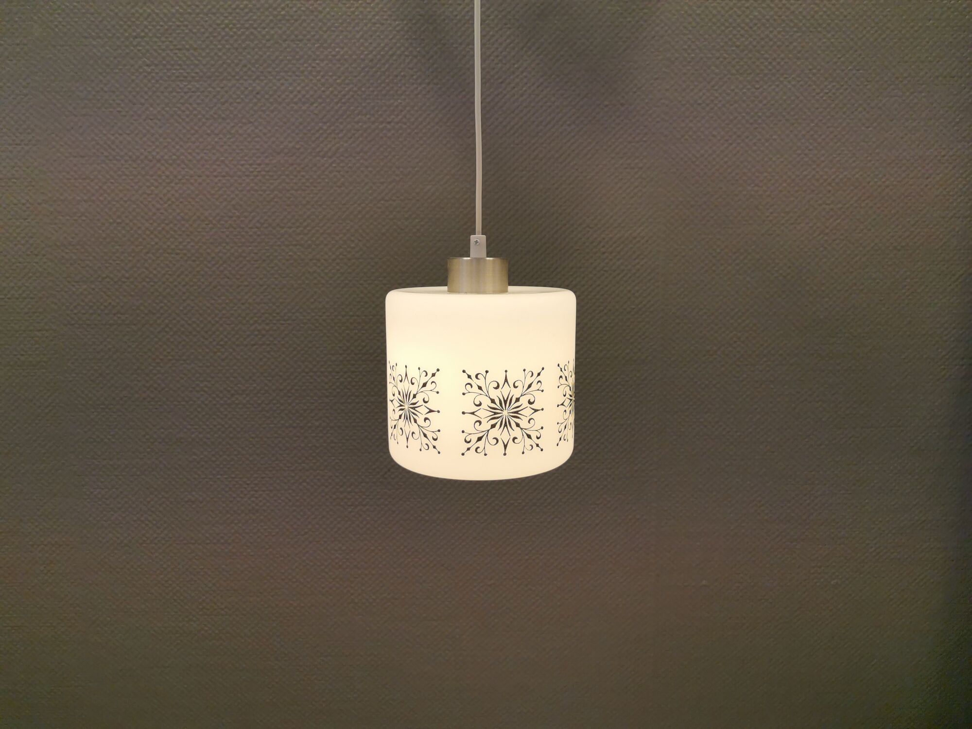 Scandinavian hanging lamp in white glass with inlayed black motifs.