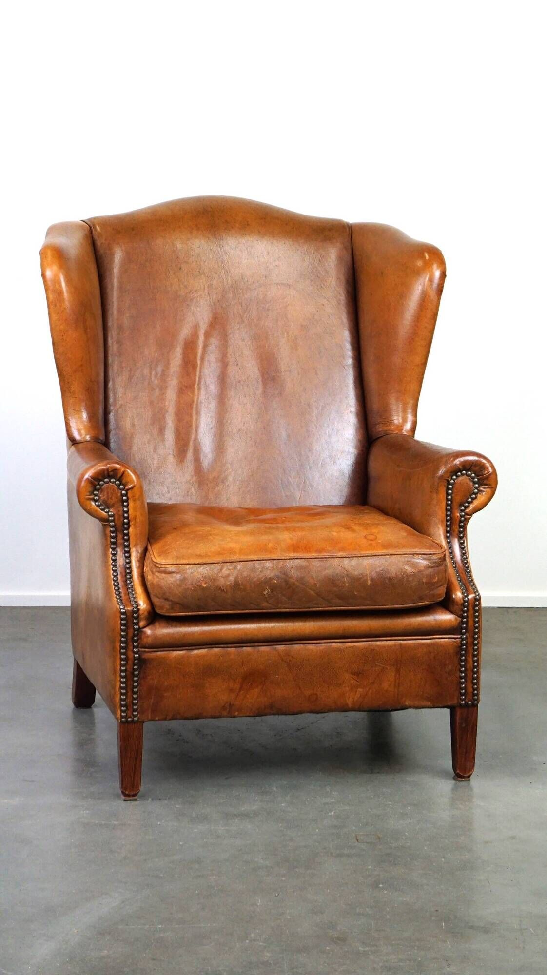 Positively lived-in sheepskin leather wing chair with pleasant seating comfort