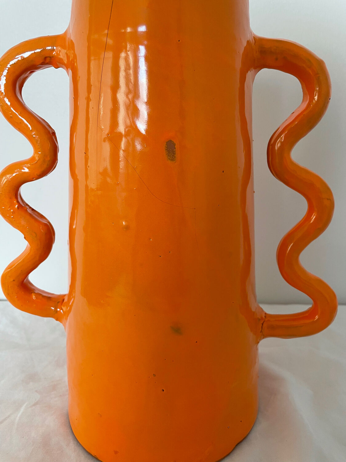 Handmade abstract orange ceramic vase with wavy handles