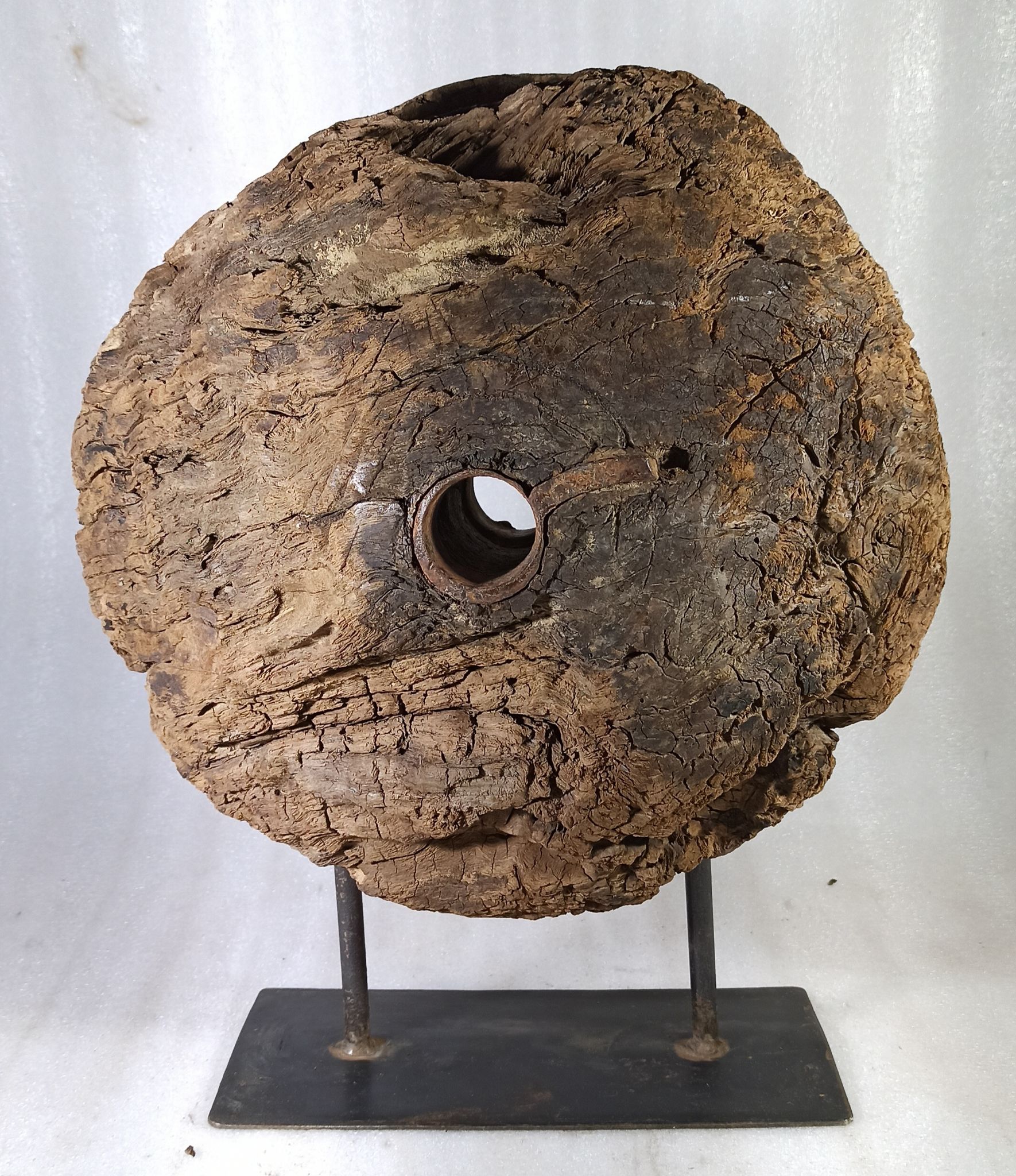 Old wooden pulley wheel on foot