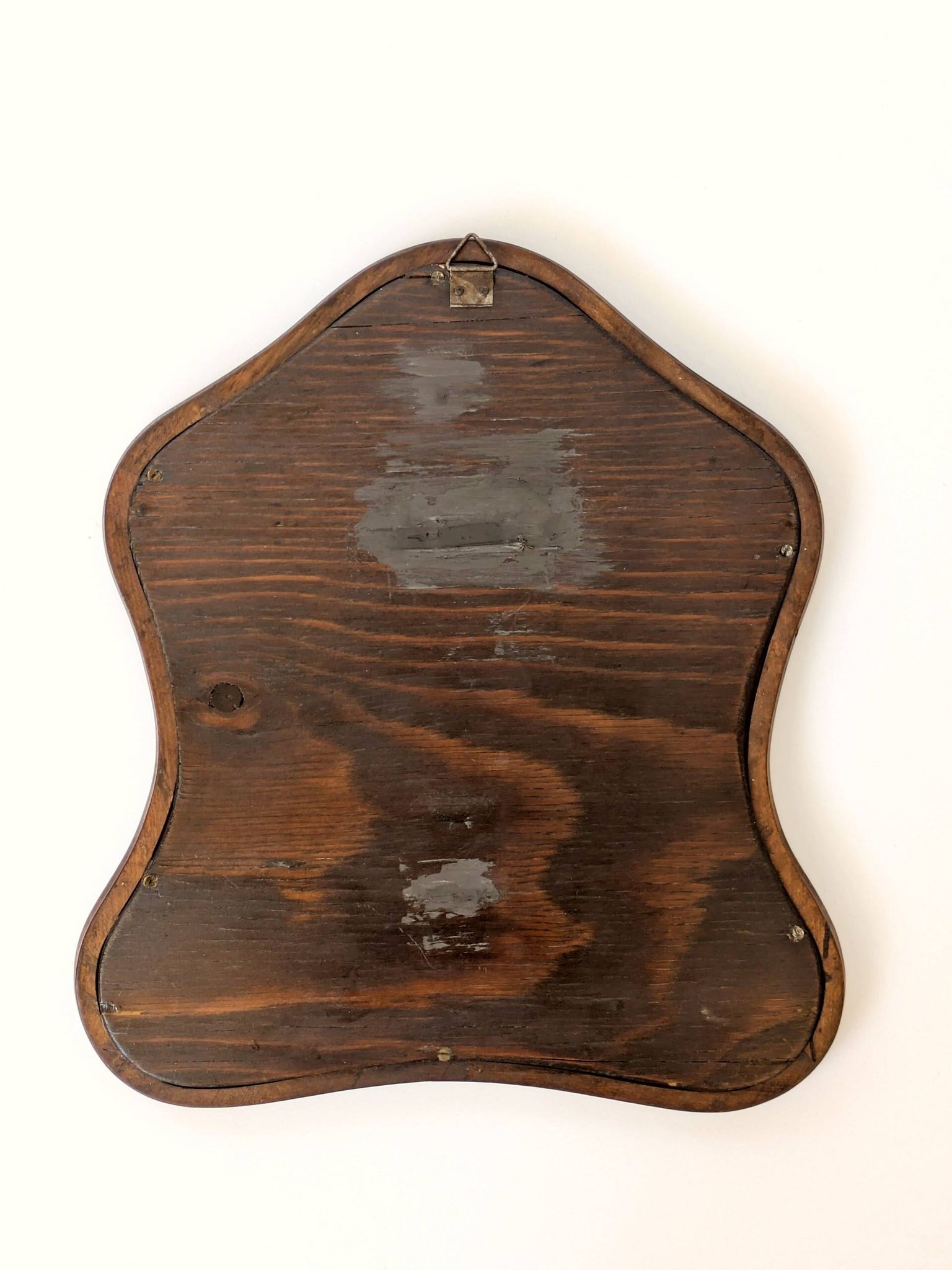 Antique wall mirror in carved wood with a wavy shape and a golden trim.