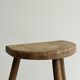 Small antique tripod stool in light wood, half-moon seat.