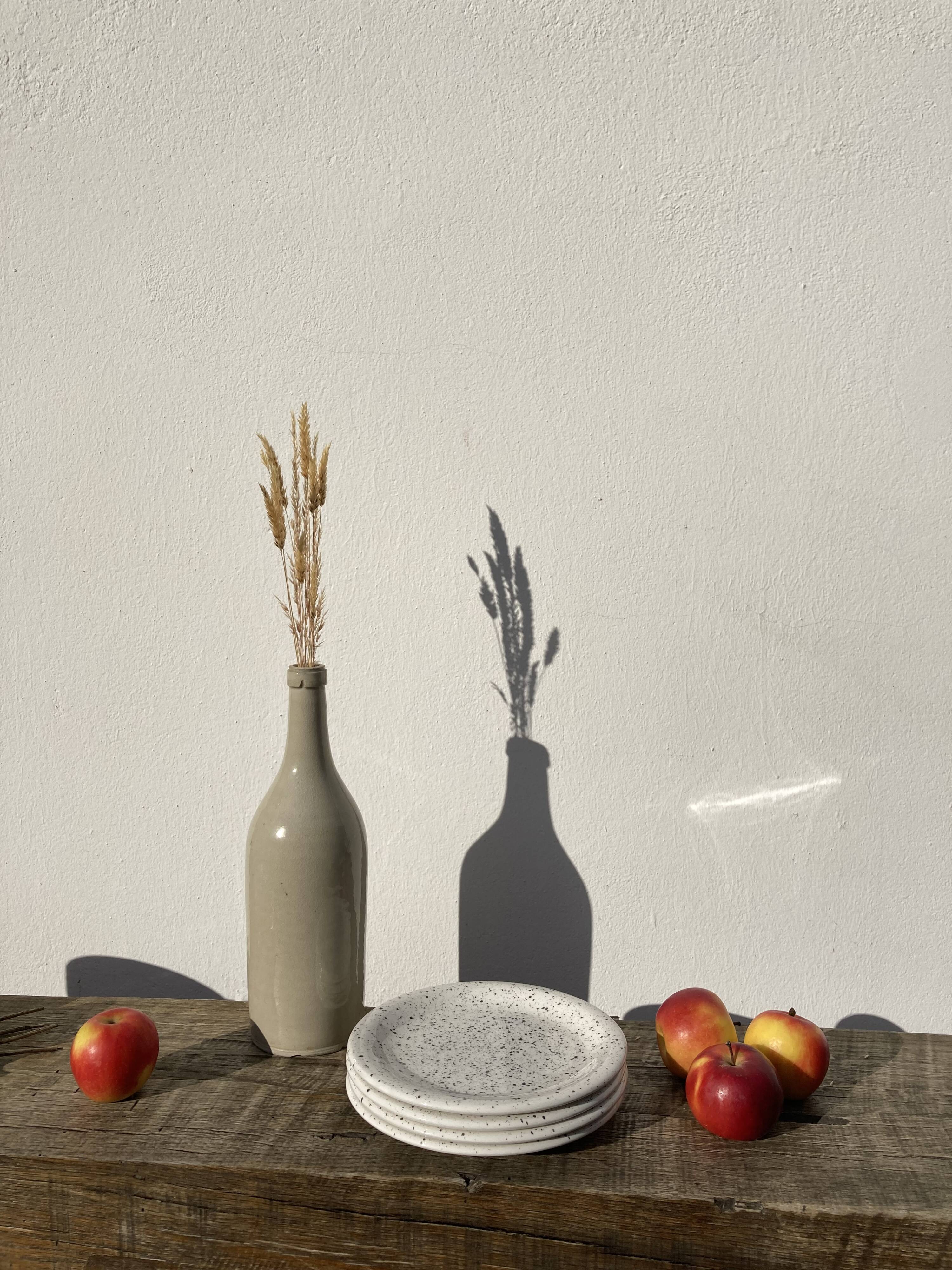4 black speckled dessert plates on a vintage white background