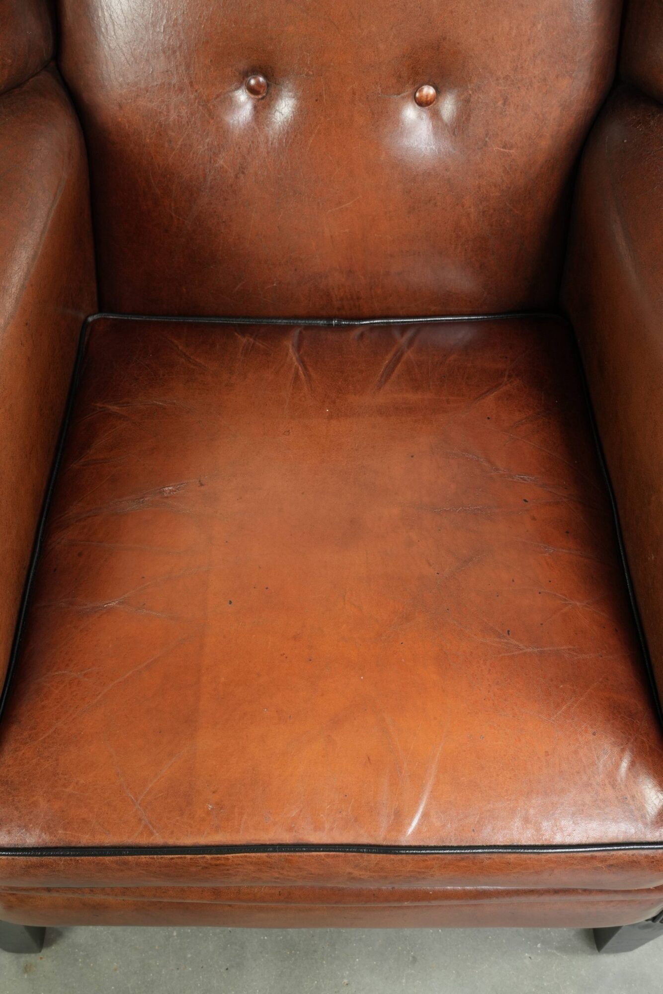 Sheepskin wingback armchair finished with black piping and a correct seat