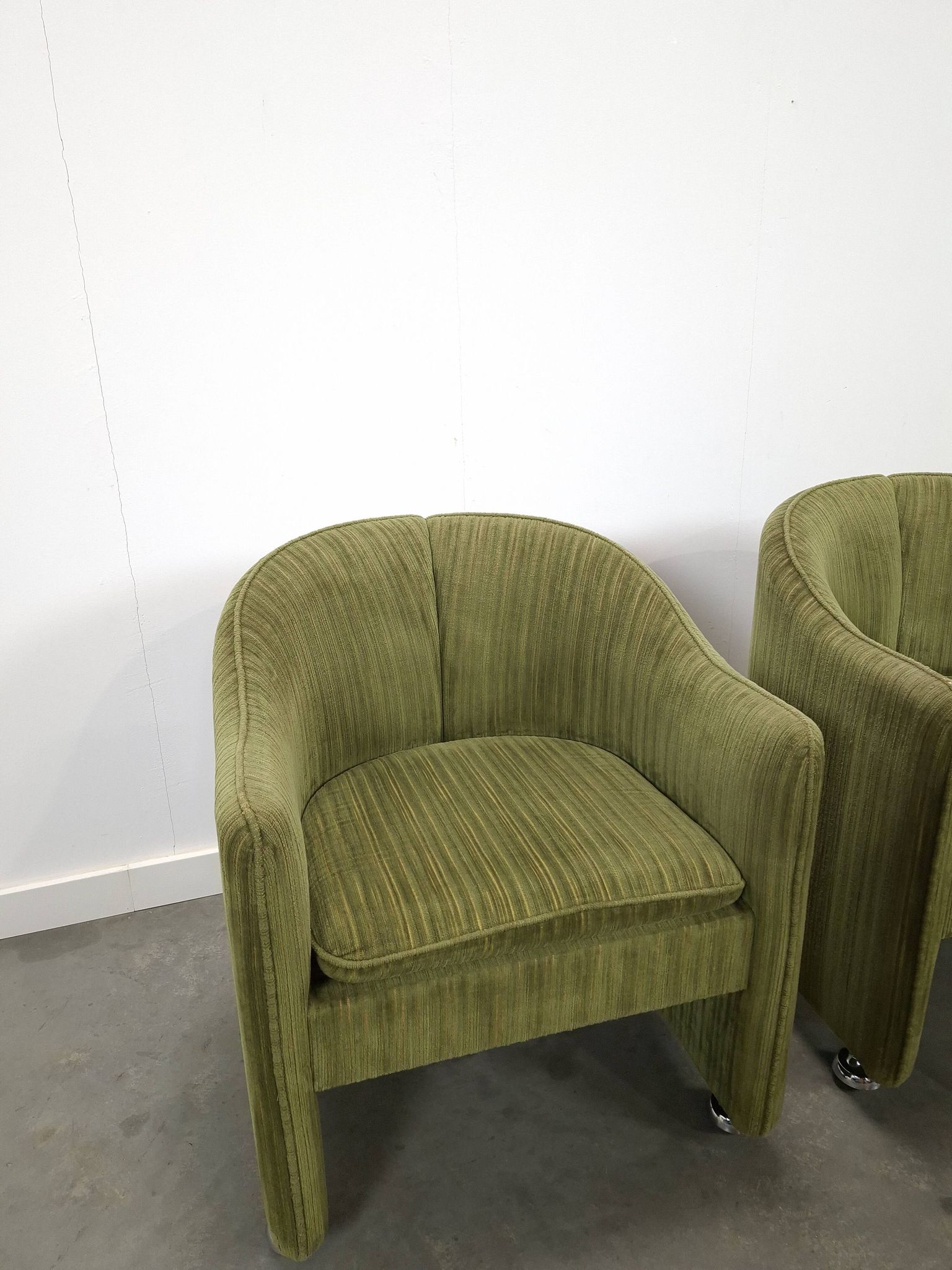 Chaises de cocktail vertes avec des roues chromées.