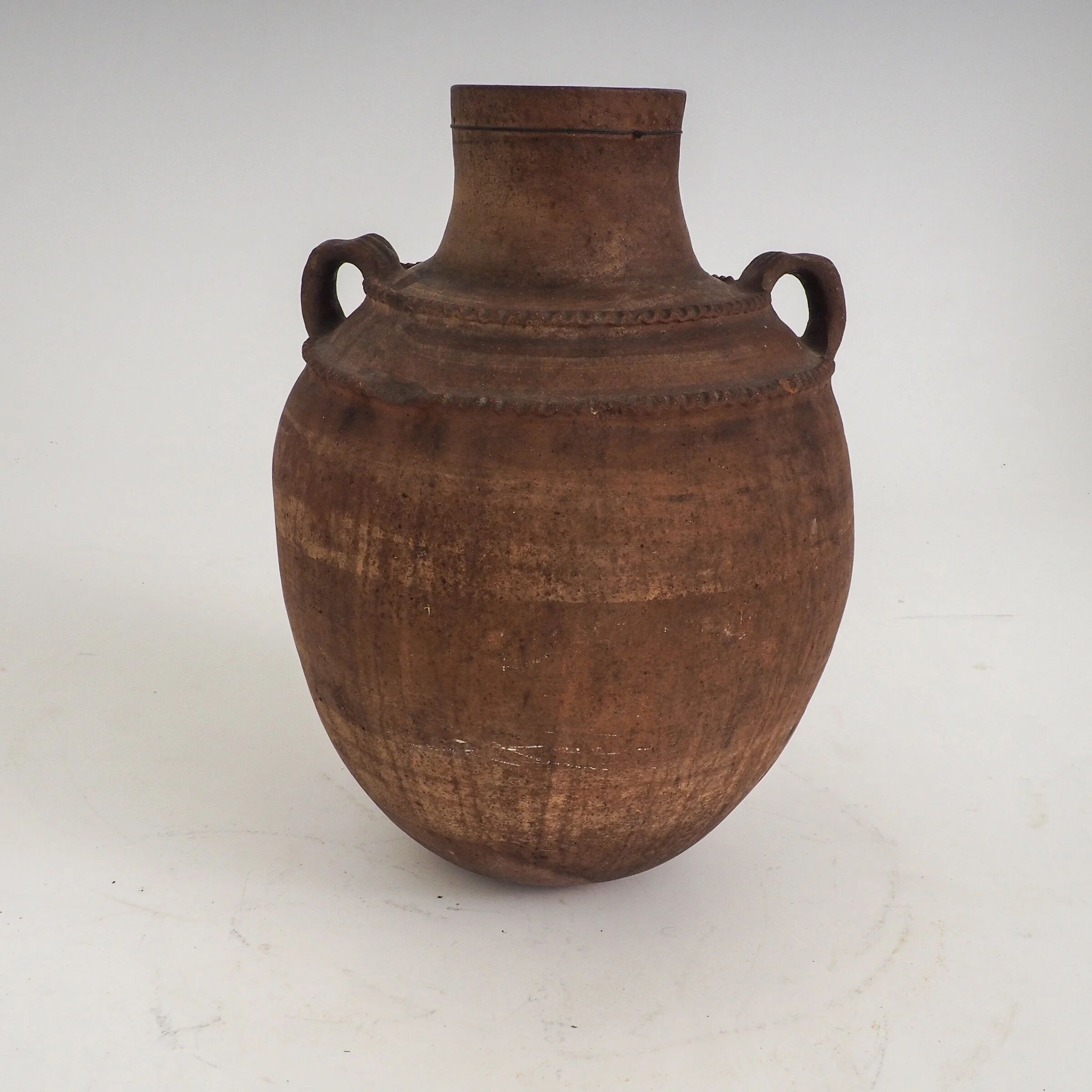 Vaisseau en terre cuite primitive avec des détails géométriques peints à la main.