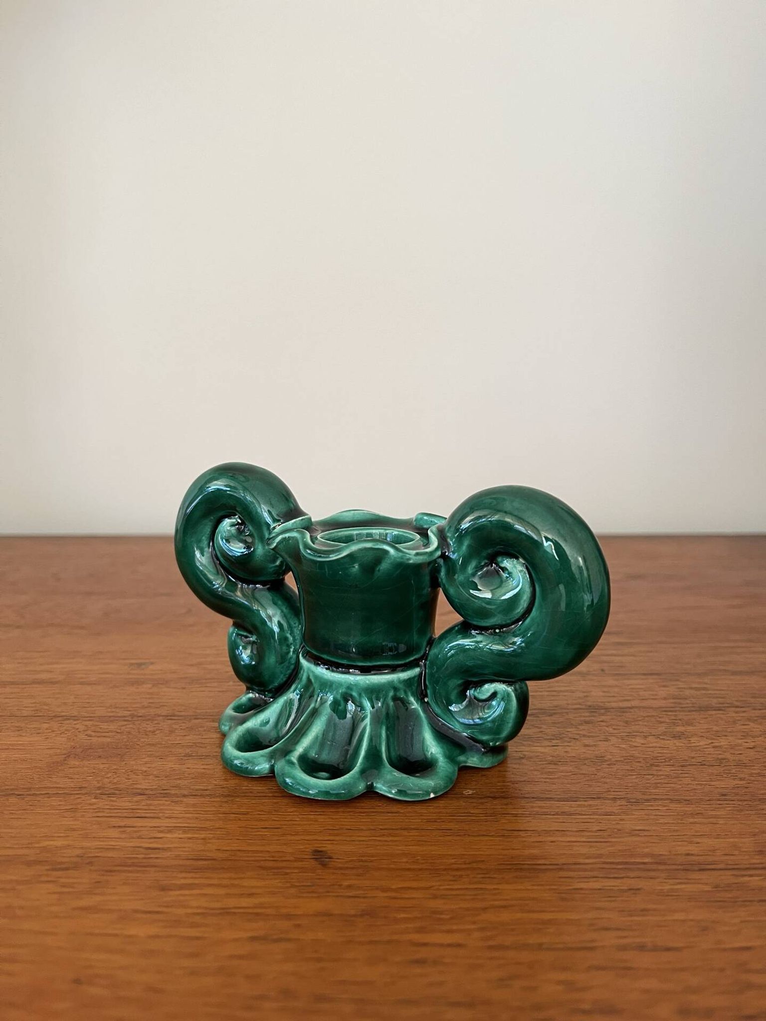 Green ceramic candlestick with curled handles.