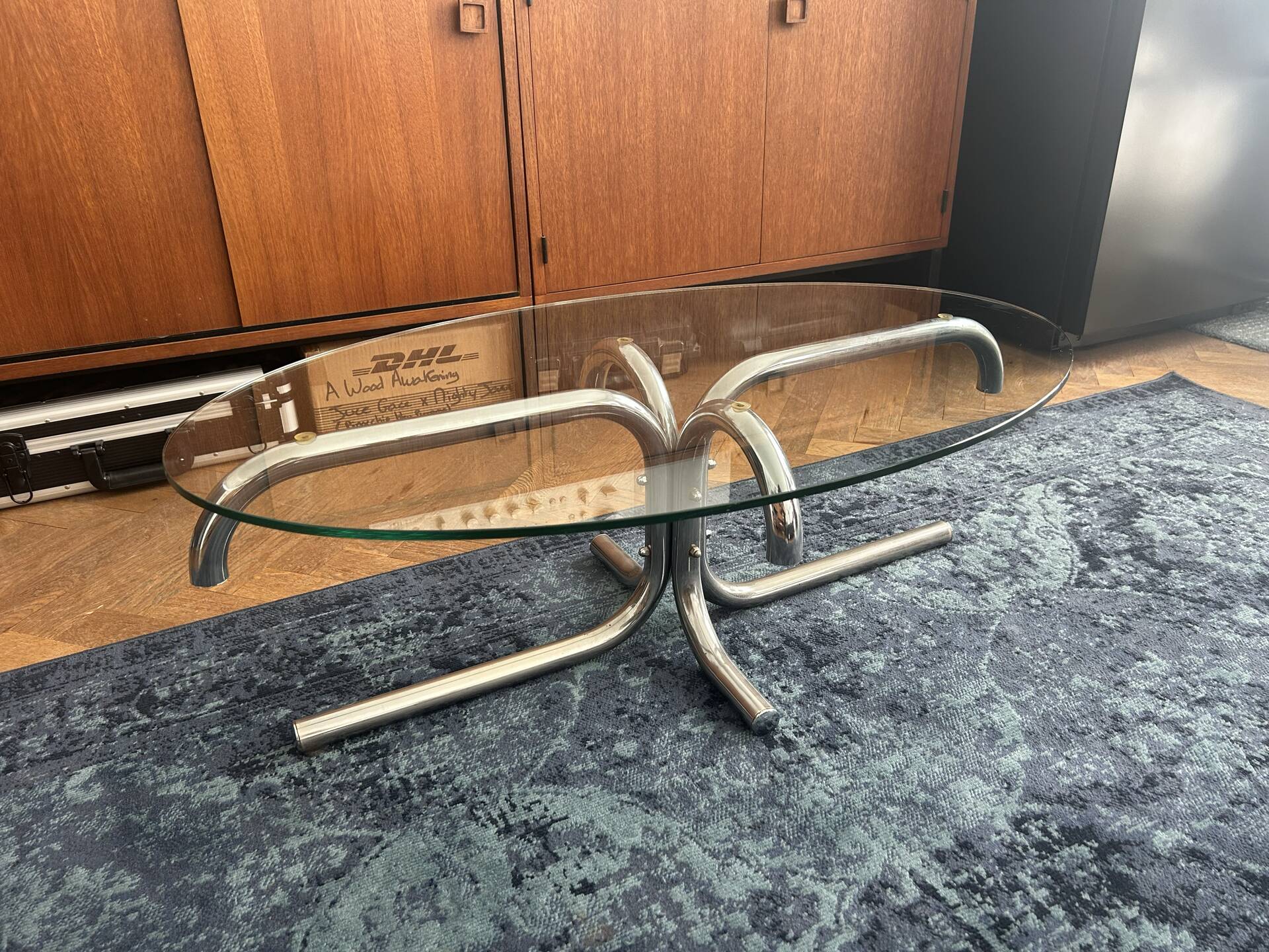 Oval glass coffee table with chrome legs, vintage 70s design.