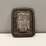 Small relief with a motif of an owl emerging from the back plate.
