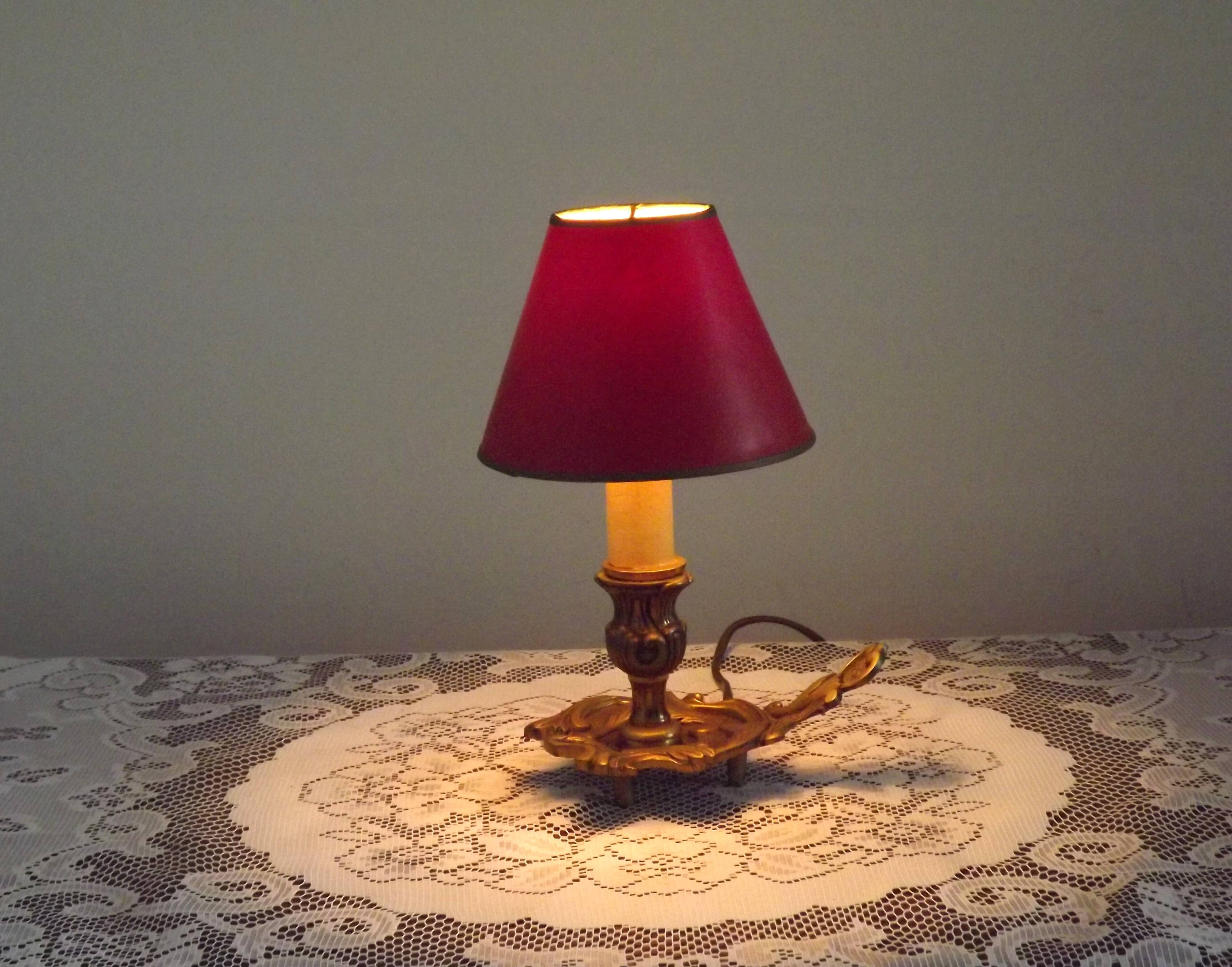 Vintage French bronze Wee Willie Winkie style lamp with red card shade.