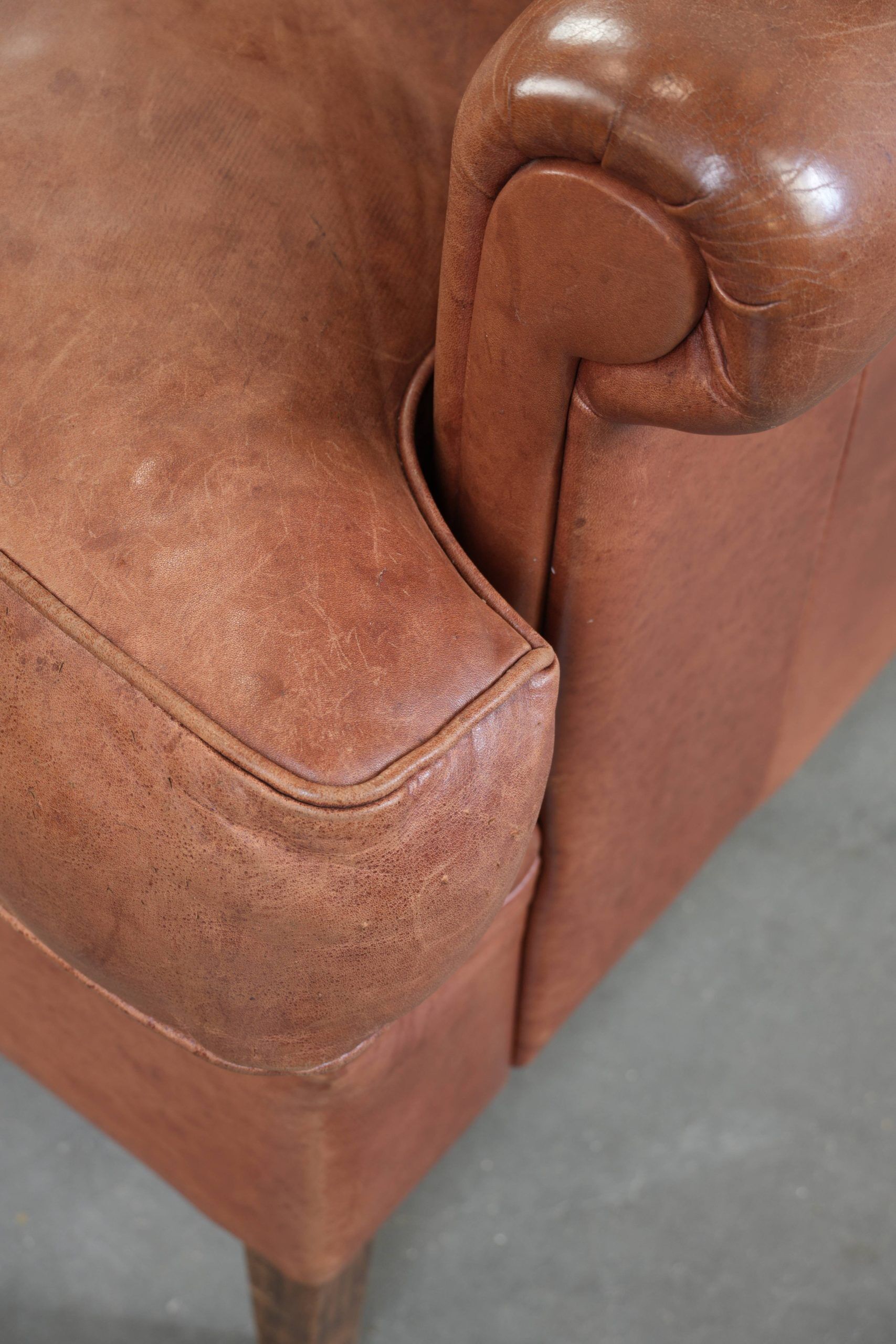 Fauteuil anglais à oreilles de couleur cognac clair en cuir de vache.