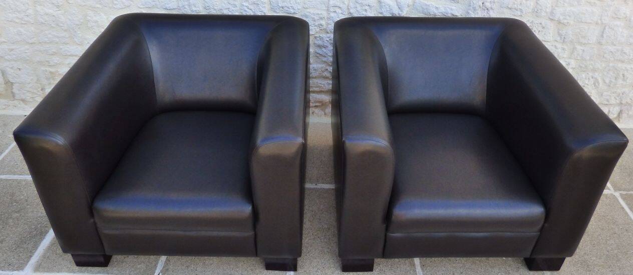 2 club armchairs with a chocolate faux leather seat and backrest and wooden legs.