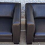 2 club armchairs with a chocolate faux leather seat and backrest and wooden legs.