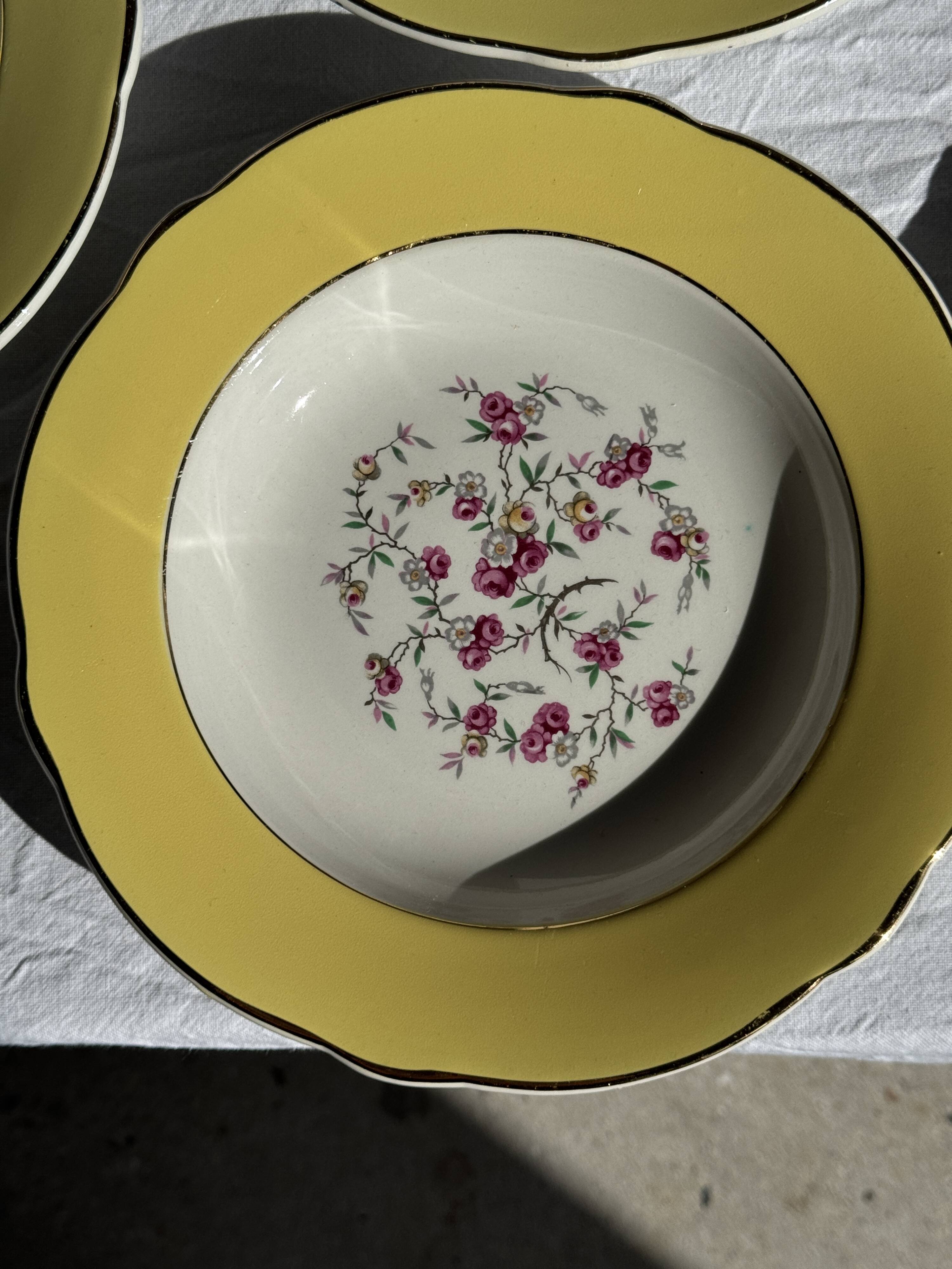 Set of 9 large vintage yellow deep plates with pink flowers and a gold rim.