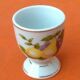 White porcelain egg cup decorated with pears / grapes.