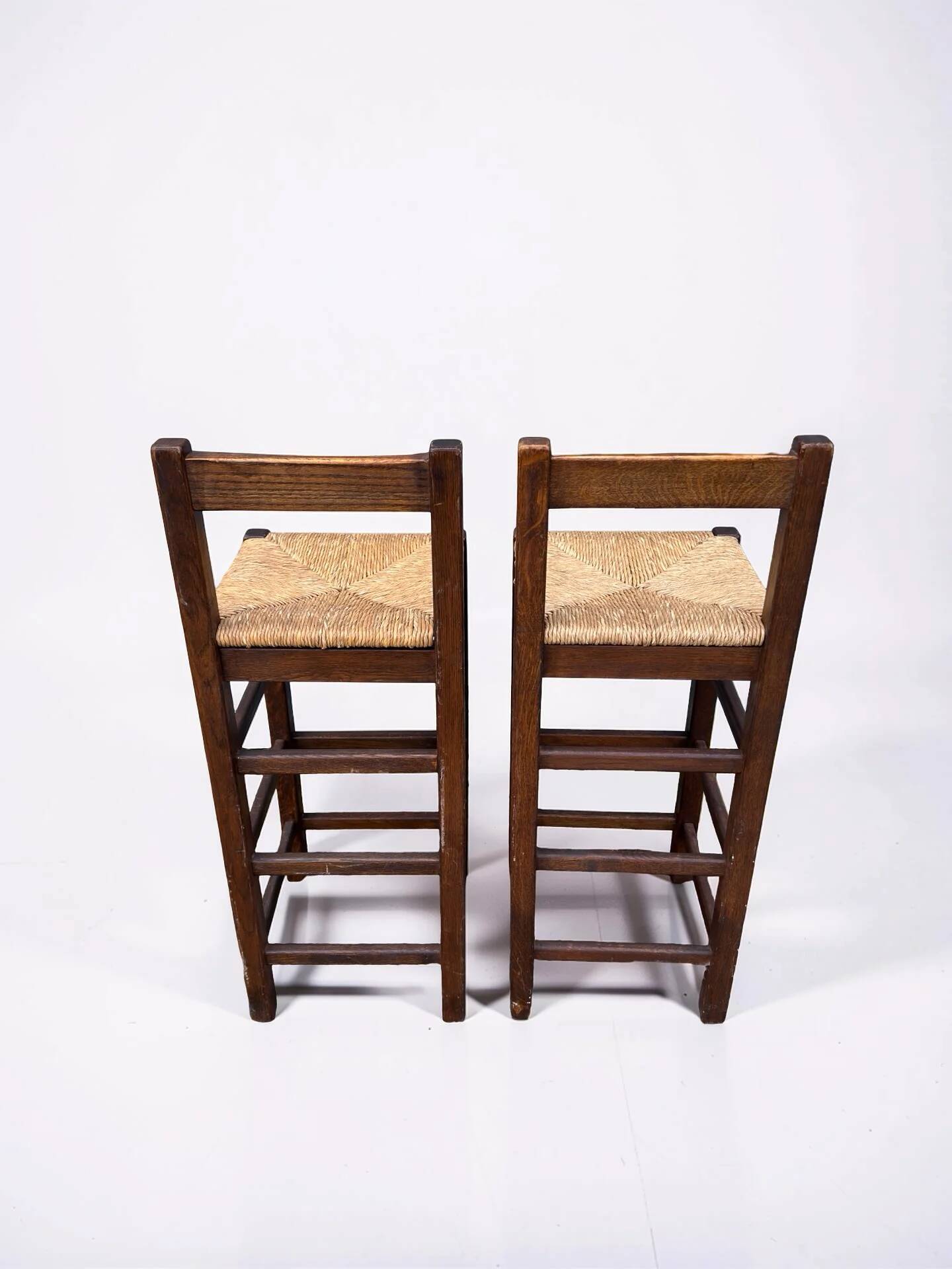 Set of 2 vintage wooden bar stools with woven straw seats.