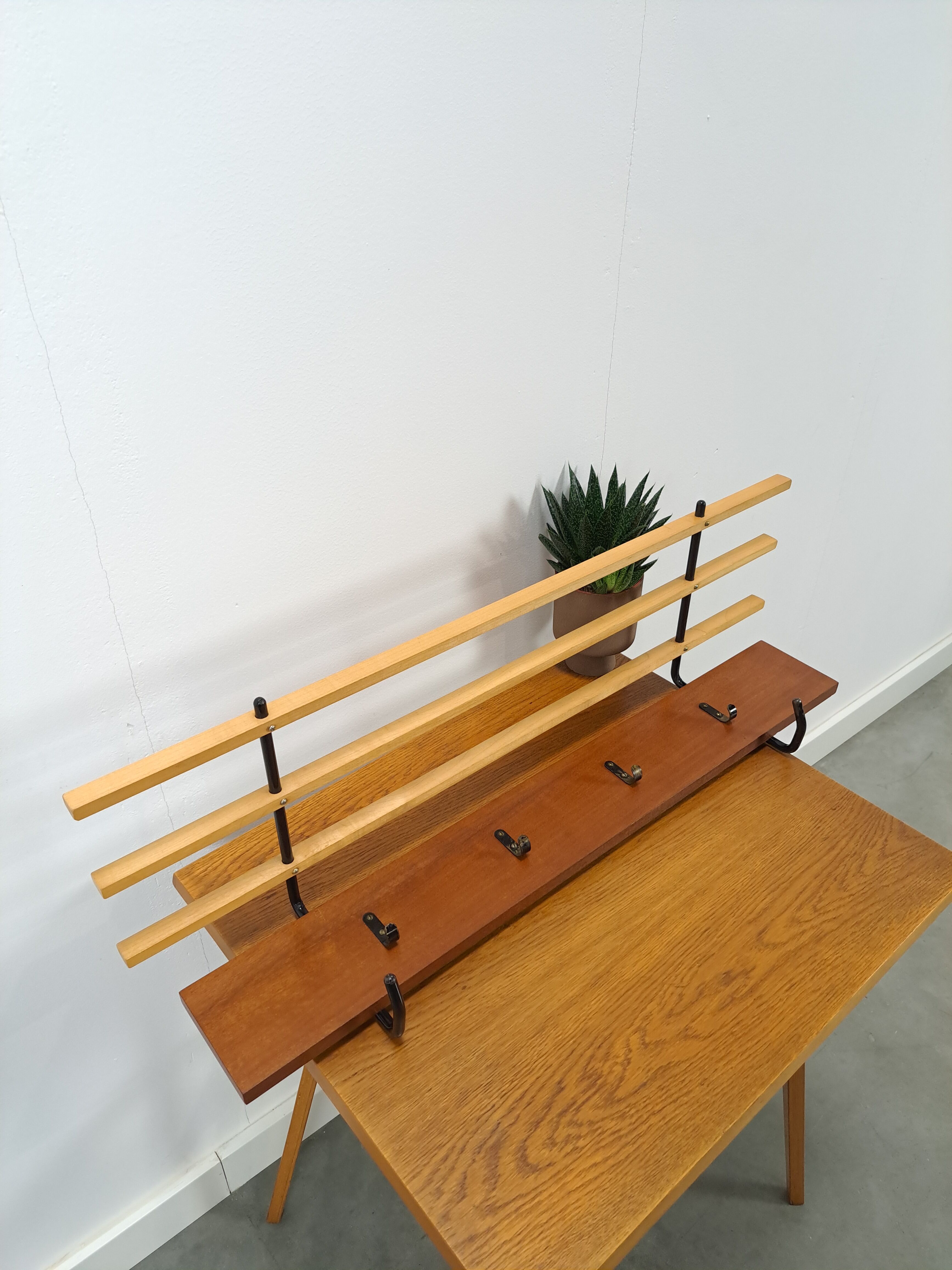 Vintage wall coat rack with black hooks and light wood