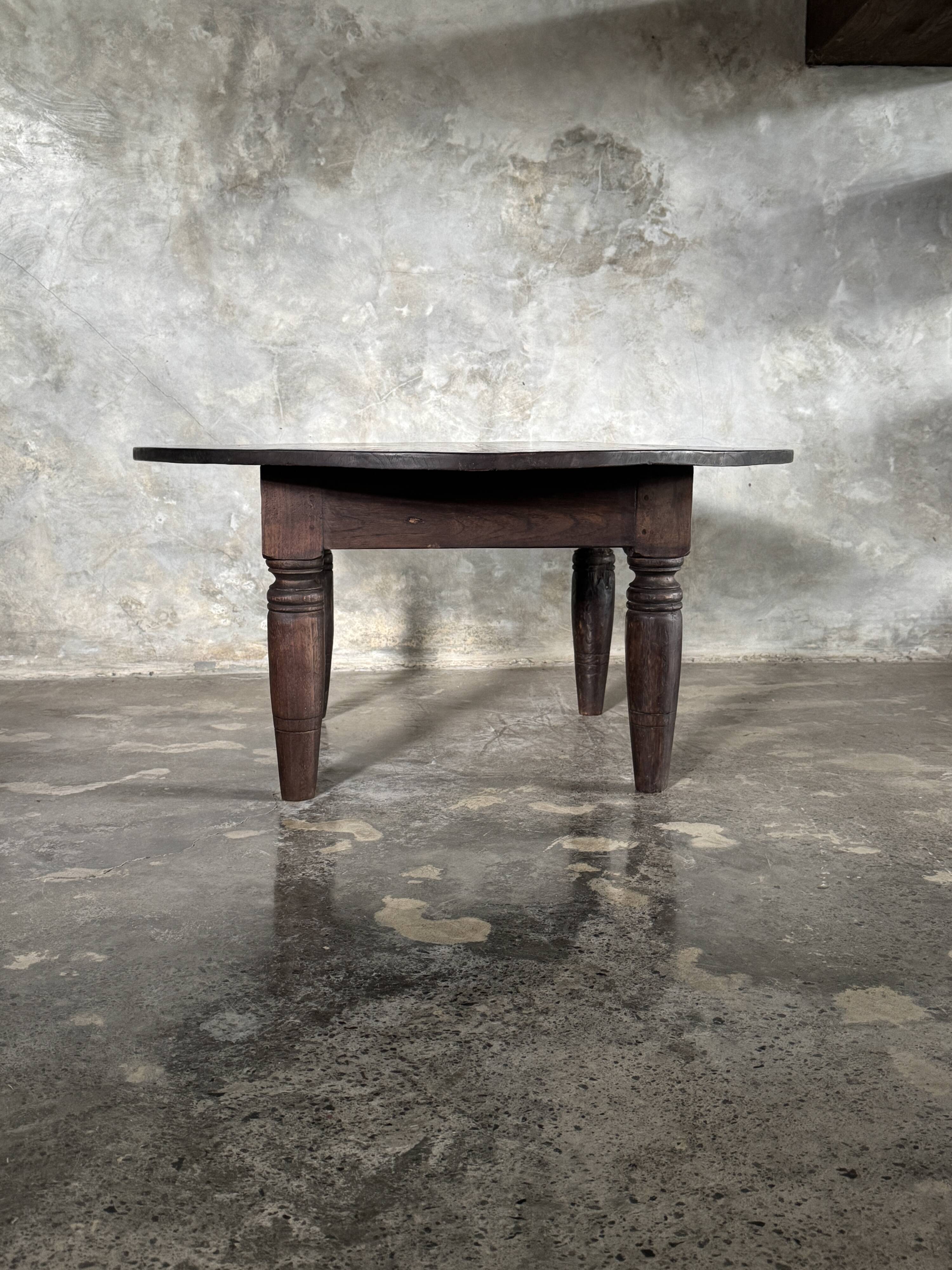 Antique round coffee table in Indonesian teak with turned legs.