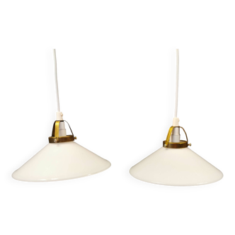 A set of hanging lamps in milky white opal glass with brass top.