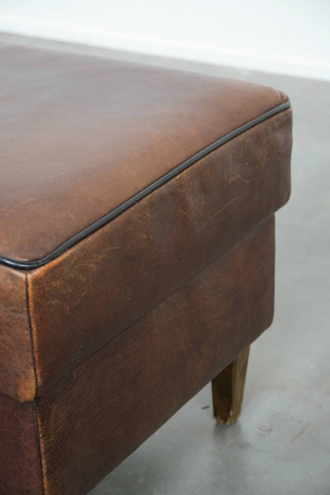 Sturdy vintage sheepskin ottoman in a beautiful large size with black piping