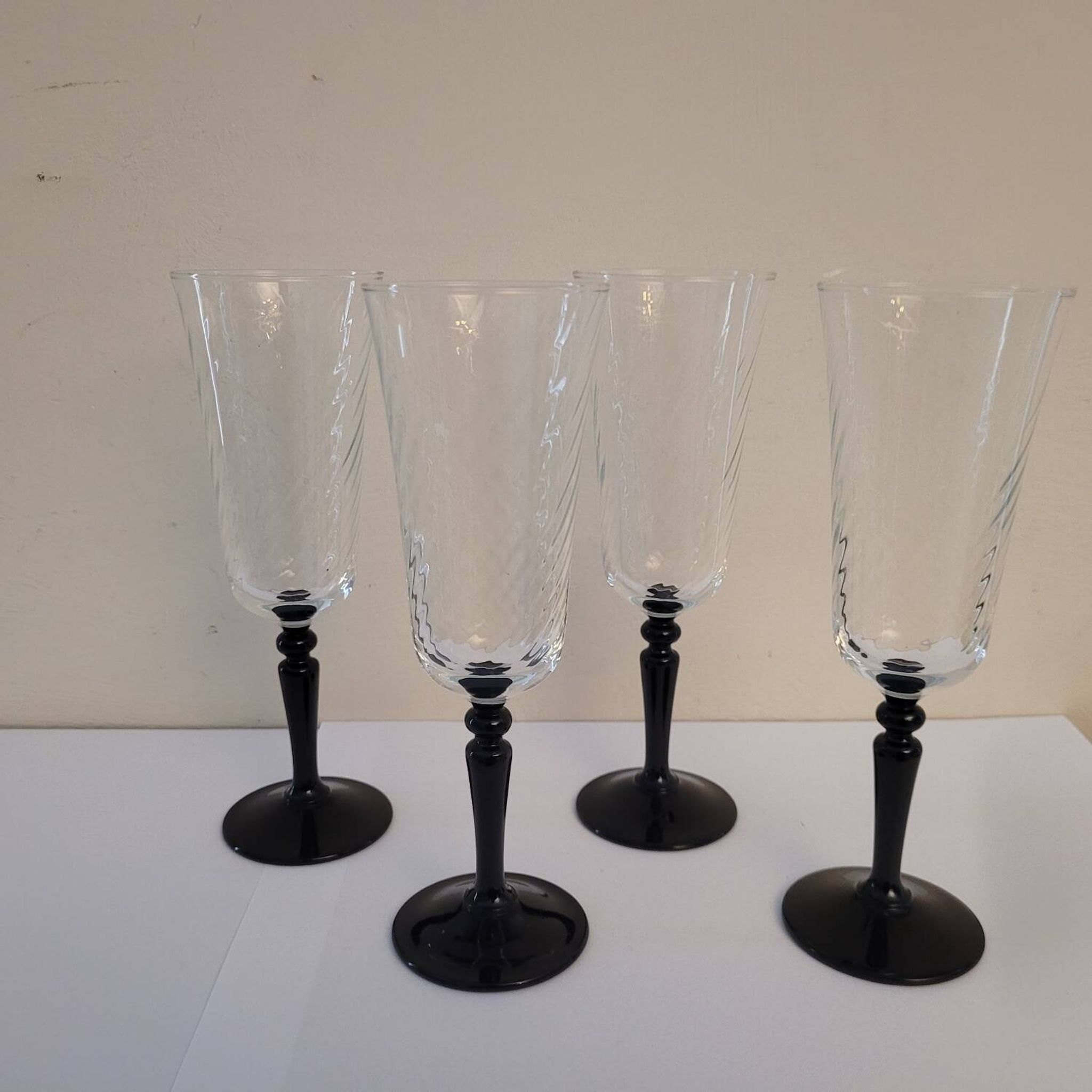 4 clear glass flutes with black stems. 1960–1970. 4 clear glass flutes with black stems.