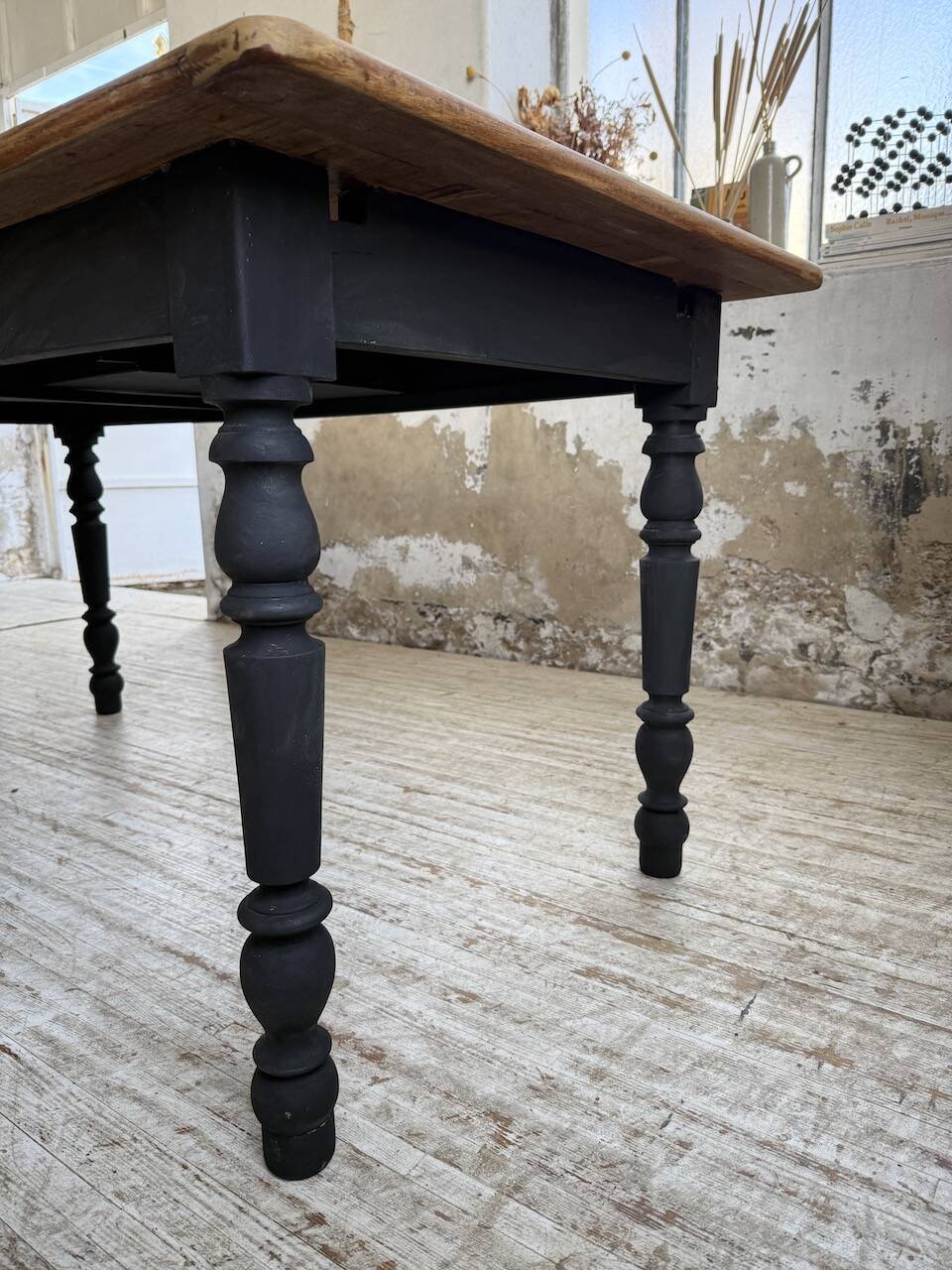 Oak farmhouse table with turned black legs.