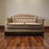Vintage beige two-seater canapé with fringes.
