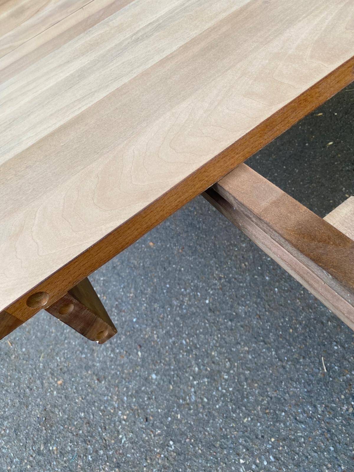 Round extendable dining table stripped in solid raw walnut with a central leg.