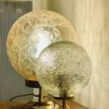 Small handcrafted globe lamp with a cracked finish and a golden brass base.
