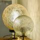 Small handcrafted globe lamp with a cracked finish and a golden brass base.