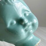 Turquoise plant pot in the shape of a vintage doll's head.