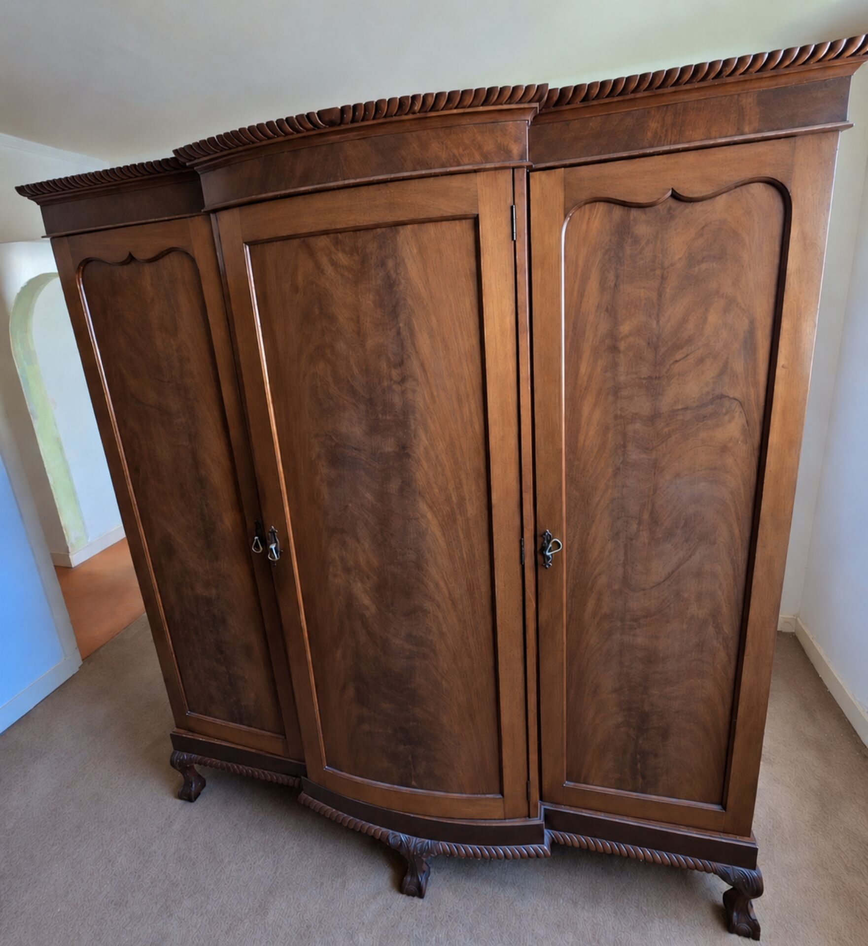 Large English-style wardrobe with a curved front and three doors.