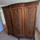 Large English-style wardrobe with a curved front and three doors.