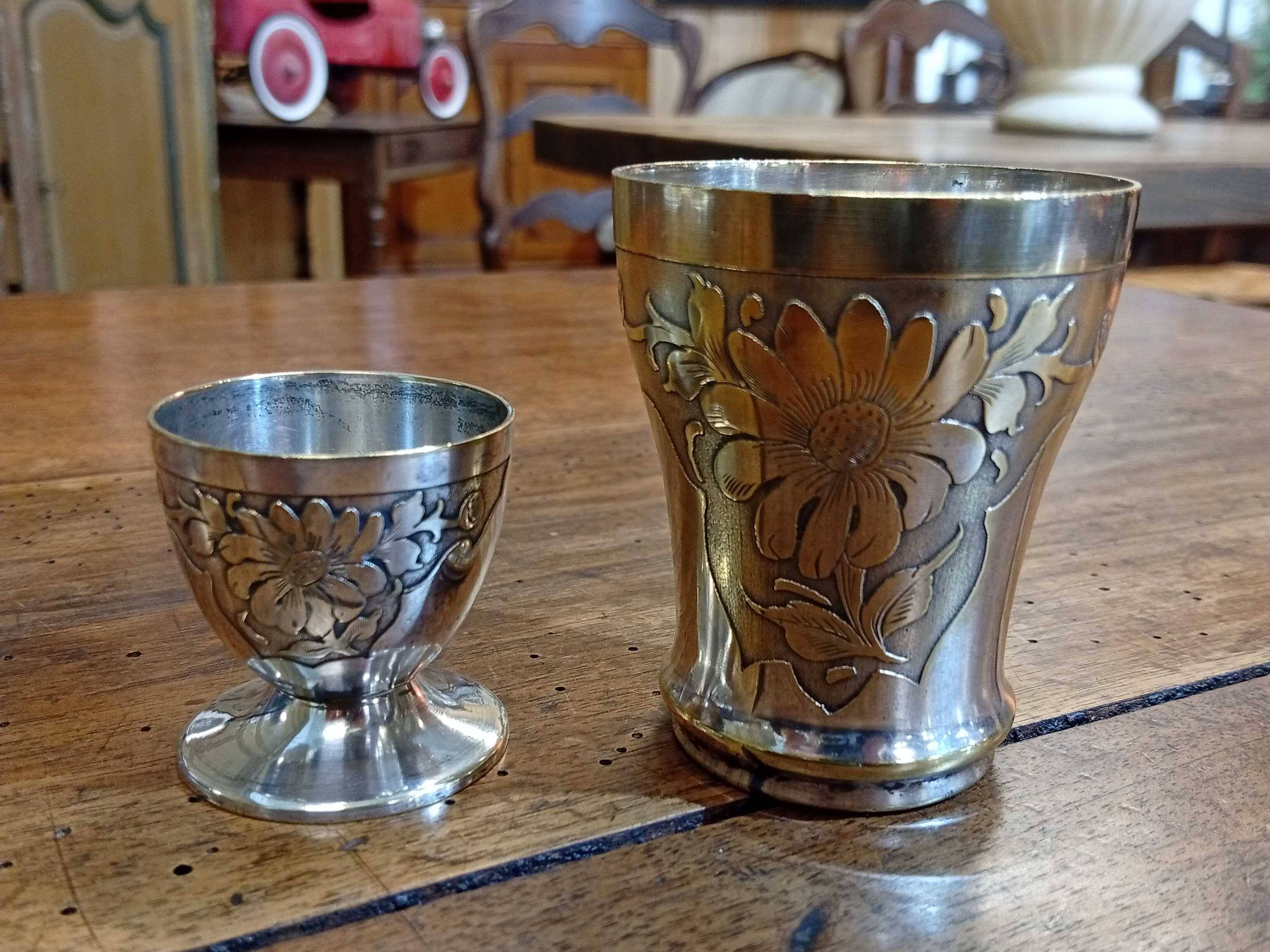 Silver-plated cup and egg cup set with floral decoration.