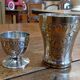 Silver-plated cup and egg cup set with floral decoration.