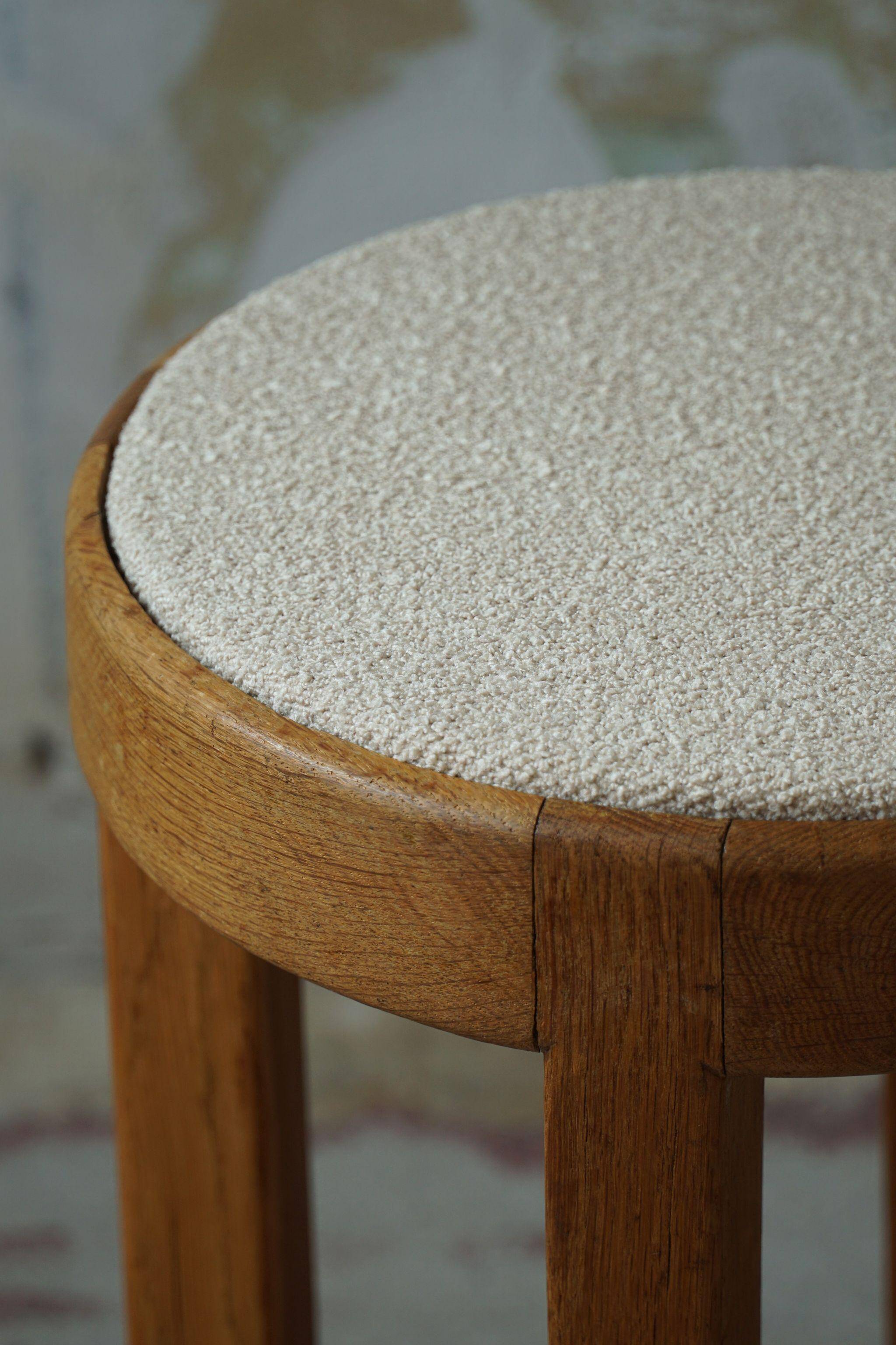 Mid-century Danish stool in oak, reupholstered in boucle wool, circa 1950.