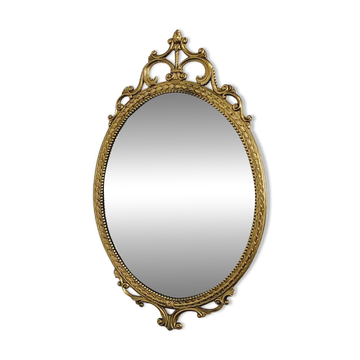 Antique oval mirror in medallion style with a brass frame.