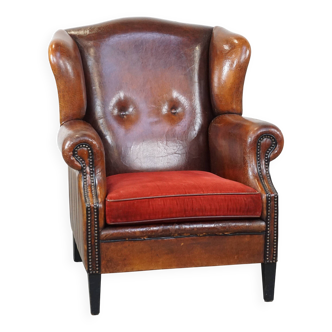 Fauteuil à oreilles en cuir de mouton avec coussin d'assise en velours côtelé rouge