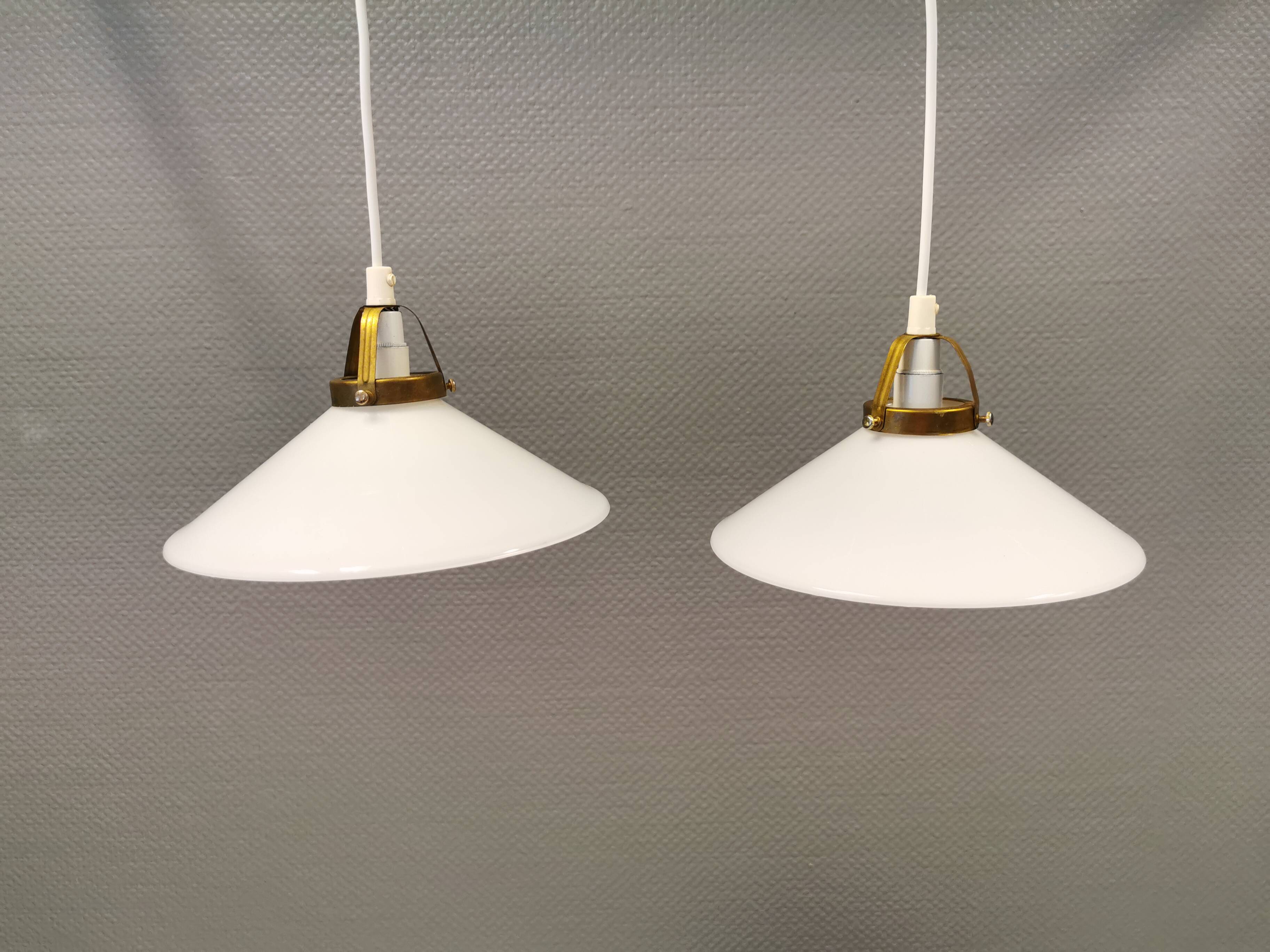 A set of hanging lamps in milky white opal glass with brass top.