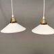 A set of hanging lamps in milky white opal glass with brass top.