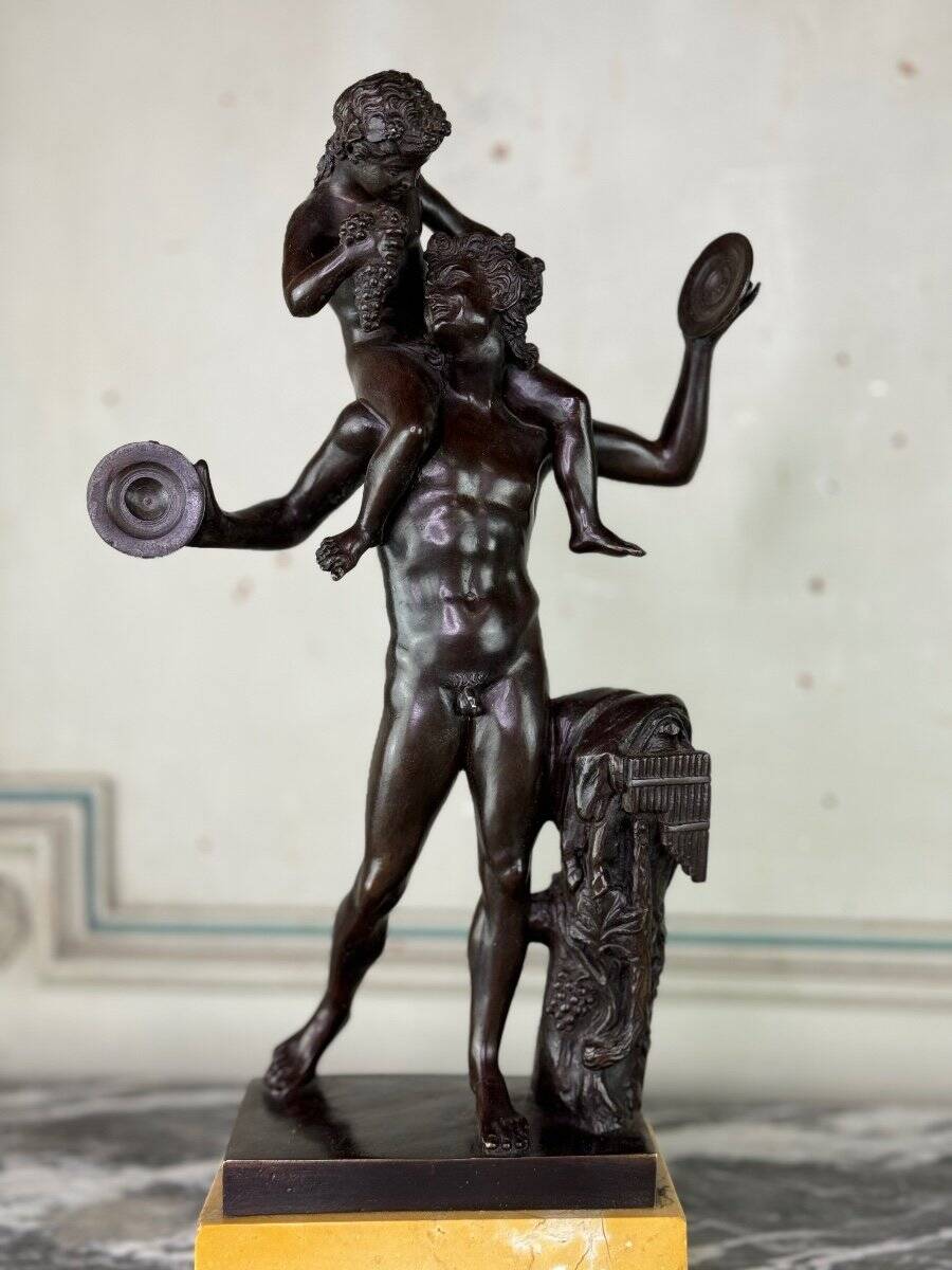 Dionysus on the shoulders of a satyr, bronze after the antique on a yellow Siena base.