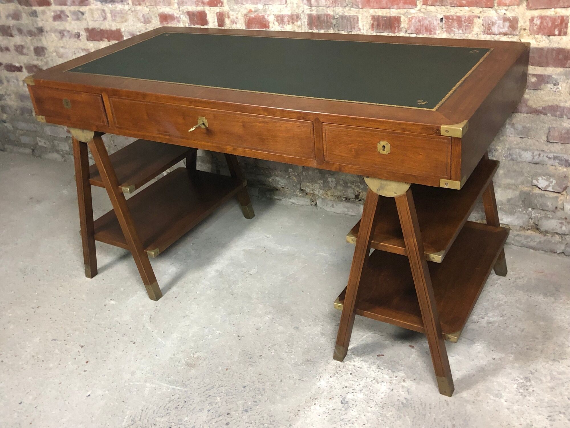 Walnut desk with green leather top resting on two trestles