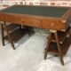 Walnut desk with green leather top resting on two trestles