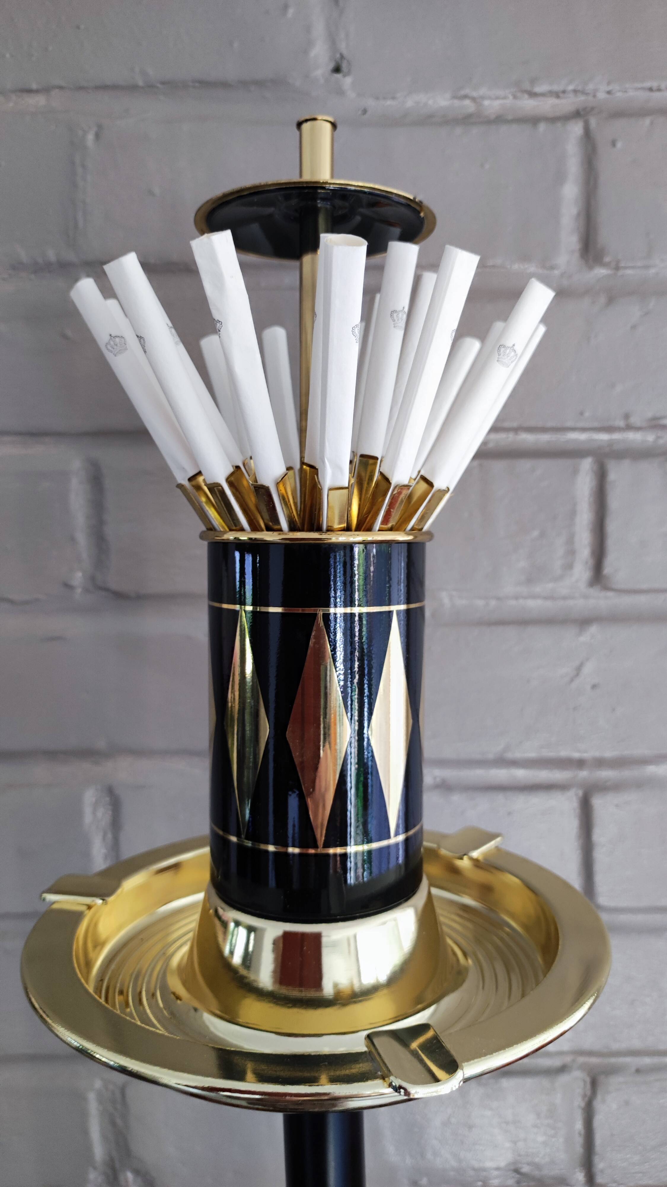 Vintage floor ashtray with a gold and black metal cigarette dispenser.